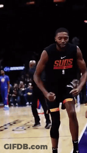 A Basketball Player Wearing A Suns Shirt Is Dancing On The Court . GIF