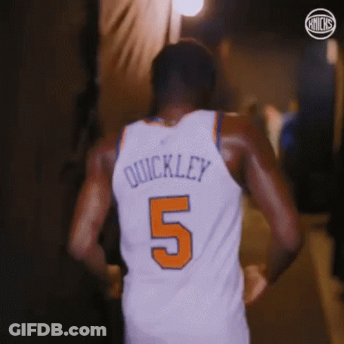 A Basketball Player Wearing A White Jersey With The Number 5 On It Is Walking Down A Hallway . GIF