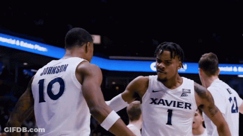 A Basketball Player Wearing A Xavier Jersey Shakes Another Player 'S Hand GIF