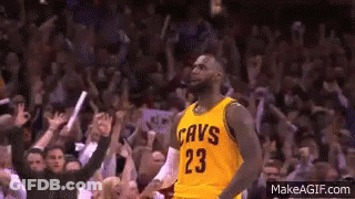A Basketball Player Wearing A Yellow Cavs Jersey Is Standing In Front Of A Crowd Of People . GIF