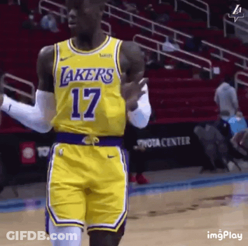 A Basketball Player Wearing A Yellow Lakers Jersey And Shorts Is Walking On The Court . GIF