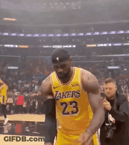 A Basketball Player Wearing A Yellow Lakers Jersey Is Walking On The Court . GIF