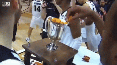 A Basketball Player Wearing Number 14 Holds A Trophy GIF