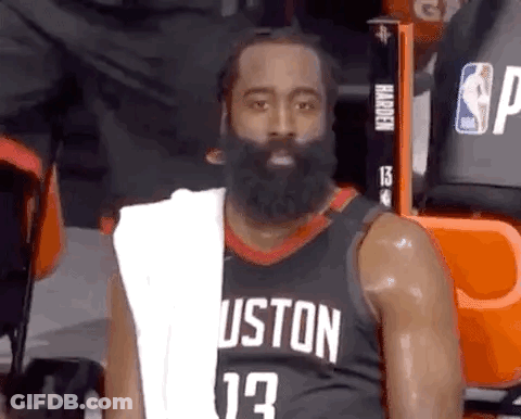 A Basketball Player With A Beard And A Towel Around His Neck Is Sitting In The Stands During A Game . GIF