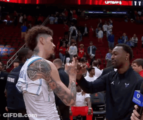A Basketball Player With A Tattoo On His Arm Shakes Hands With Another Man GIF