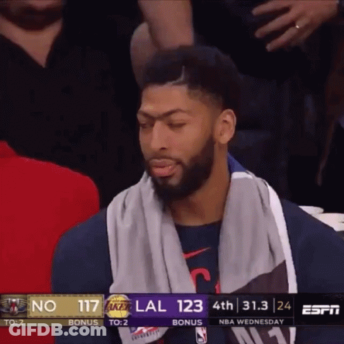 A Basketball Player With A Towel Around His Neck Sits In The Stands During A Game GIF
