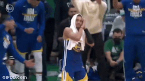 A Basketball Player With A Towel Wrapped Around His Head Is Standing In Front Of A Crowd Of People . GIF