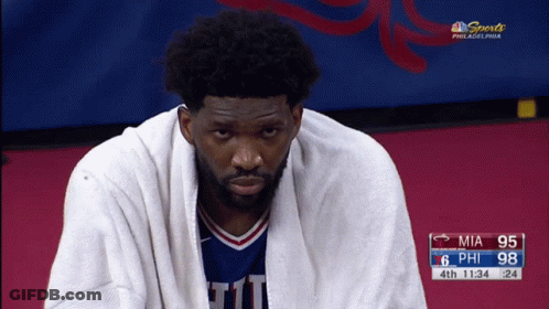 A Basketball Player With A Towel Wrapped Around His Neck Is Sitting On The Court GIF