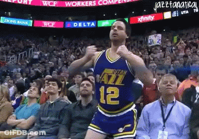 A Basketball Player With The Number 12 On His Jersey Is Dancing In Front Of A Crowd GIF