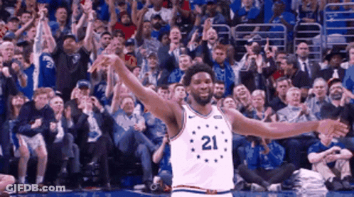 A Basketball Player With The Number 21 On His Jersey Is Standing In Front Of A Crowd GIF