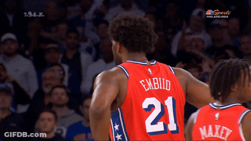 A Basketball Player With The Number 21 On His Jersey Stands In Front Of A Crowd GIF
