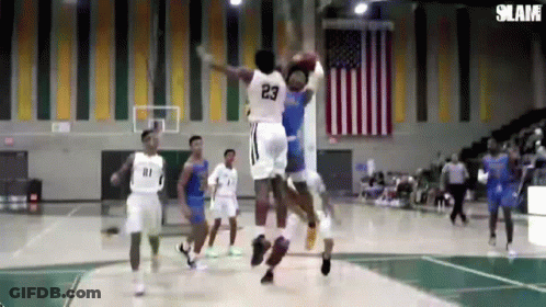 A Basketball Player With The Number 23 On His Jersey Is Jumping Over Another Player GIF