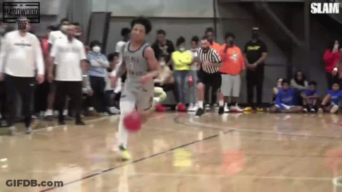 A Basketball Player With The Number 7 On His Jersey Is Dribbling The Ball On A Court GIF
