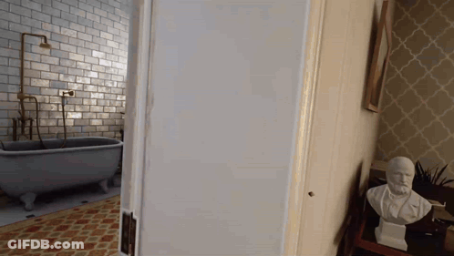 A Bathroom With A Bathtub And A Statue Of A Man On A Table GIF