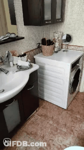A Bathroom With A Sink And A Washer GIF