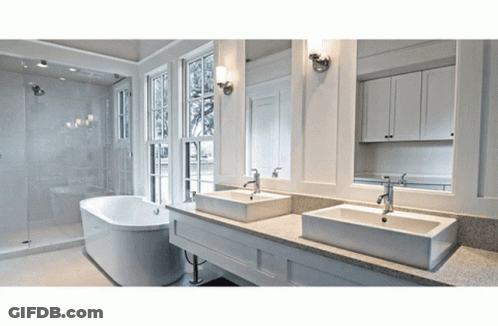 A Bathroom With Two Sinks And A Bathtub And Two Mirrors GIF