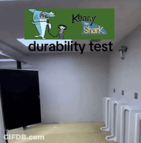 A Bathroom With Urinals And A Kenny The Shark Poster On The Wall GIF
