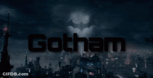 A Batman Logo Is Projected On A City Skyline GIF