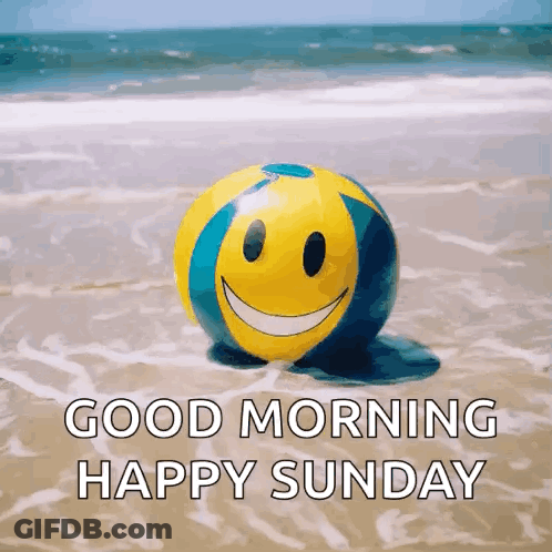 A Beach Ball With A Smiley Face On It Is On The Beach And Says `` Good Morning Happy Sunday '' . GIF