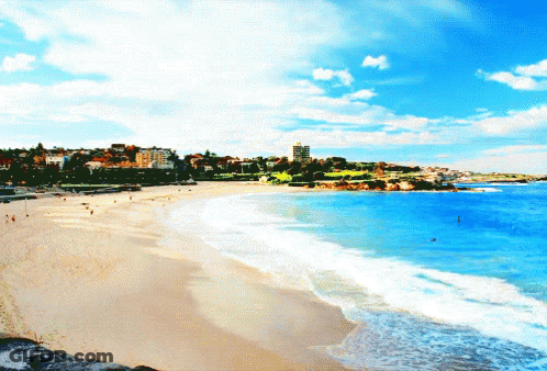 A Beach With A City In The Background And A Blue Sky GIF