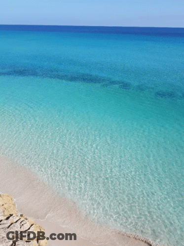 A Beach With Turquoise Water And A Blue Sky GIF