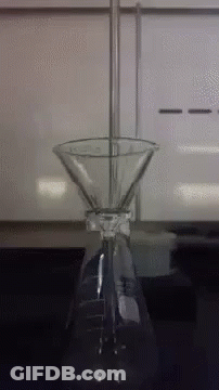 A Beaker With A Funnel Attached To It Is On A Table GIF