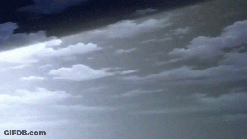 A Beam Of Light Is Shining Through The Clouds In The Sky . GIF