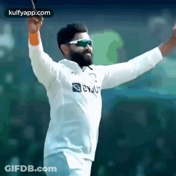 A Bearded Man Wearing Sunglasses And A White Shirt Is Holding A Bat In His Hand . GIF