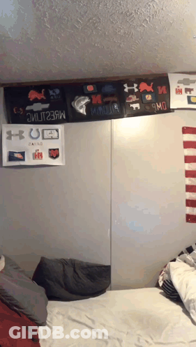 A Bed In A Dorm Room With A Bunch Of Stickers On The Wall GIF