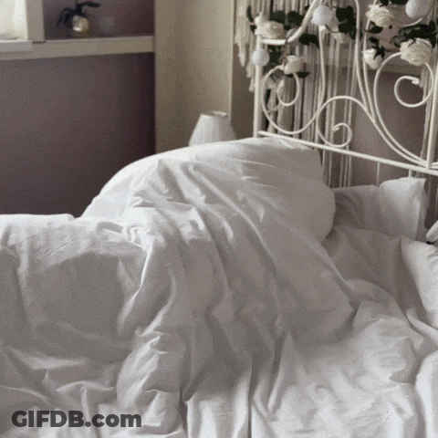 A Bed With White Sheets And Pillows And A White Headboard GIF