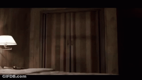 A Bedroom With A Bed And A Lamp And A Striped Door GIF