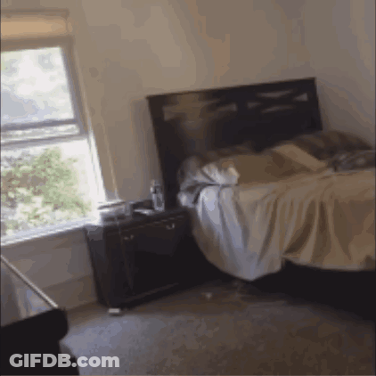 A Bedroom With A Bed And A Nightstand GIF
