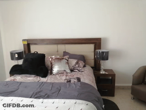 A Bedroom With A Bed And Two Lamps And A Pillow That Says Eiffel Tower GIF