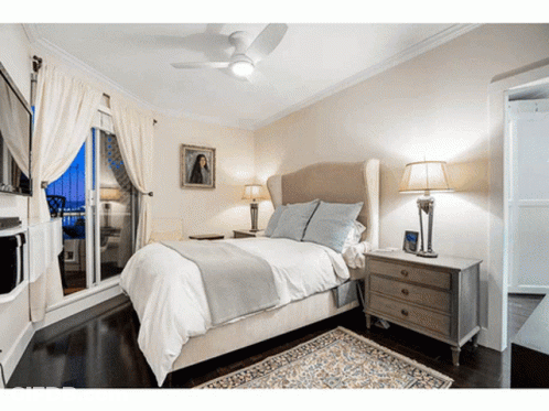 A Bedroom With A Ceiling Fan And A Painting On The Wall GIF