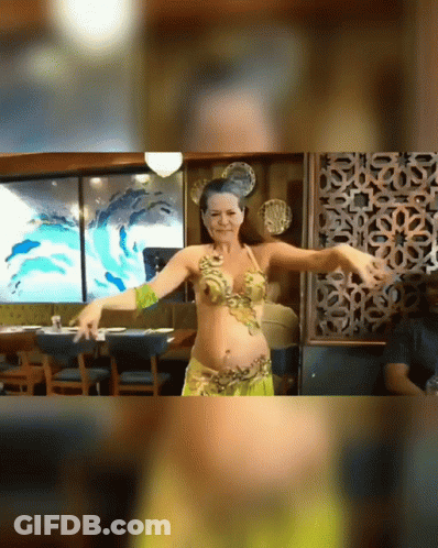 A Belly Dancer Is Dancing In Front Of A Painting Of Dolphins GIF