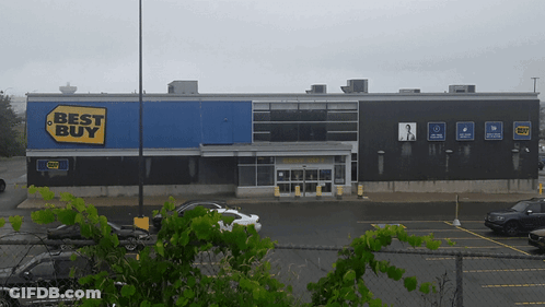A Best Buy Store With Cars Parked In Front GIF