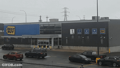 A Best Buy Store With Cars Parked In Front GIF