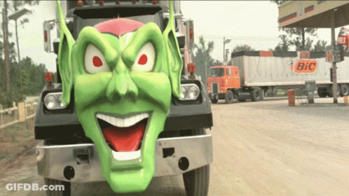 A Bic Truck Is Parked Next To A Truck With A Green Face On It GIF