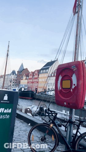 A Bicycle Is Parked Next To A Sign That Says Affald GIF