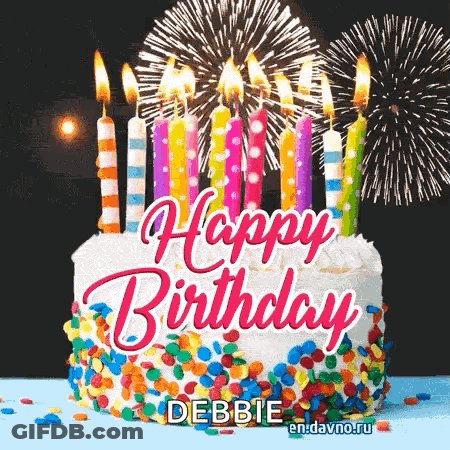 A Birthday Cake With Candles And Fireworks Behind It GIF