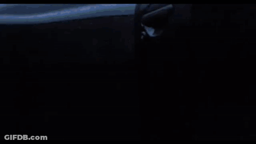 A Black Airplane Is Flying Through A Cloudy Sky . GIF