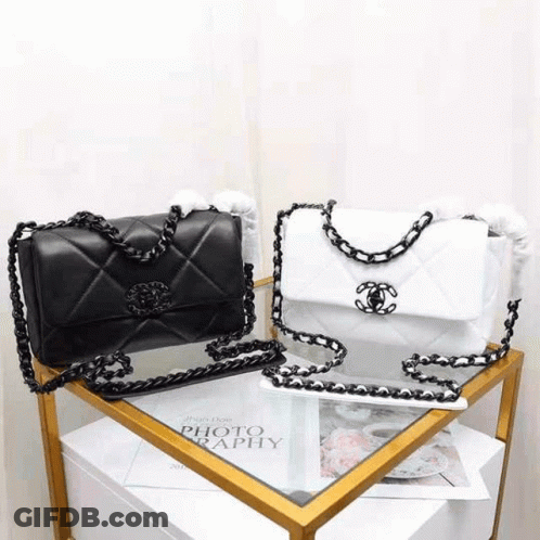 A Black And White Chanel Purse Is Sitting On Top Of A Table . GIF