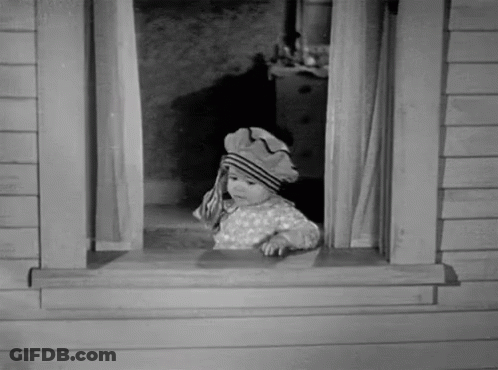 A Black And White Photo Of A Baby Wearing A Hat Looking Out Of A Window GIF