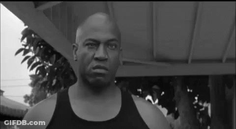 A Black And White Photo Of A Bald Man Wearing A Black Tank Top . GIF