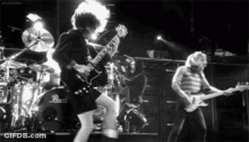 A Black And White Photo Of A Band Playing Guitars On Stage . GIF