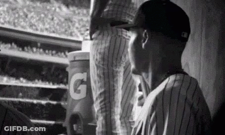 A Black And White Photo Of A Baseball Player In A Dugout . GIF