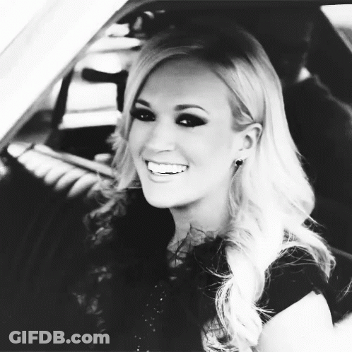 A Black And White Photo Of A Blonde Woman Smiling In A Car GIF