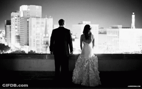 A Black And White Photo Of A Bride And Groom Looking At A City Skyline GIF