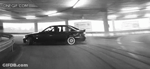 A Black And White Photo Of A Car Driving Down A Parking Garage . GIF