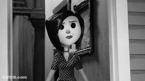 A Black And White Photo Of A Cartoon Doll In A Polka Dot Dress Standing In A Doorway . GIF